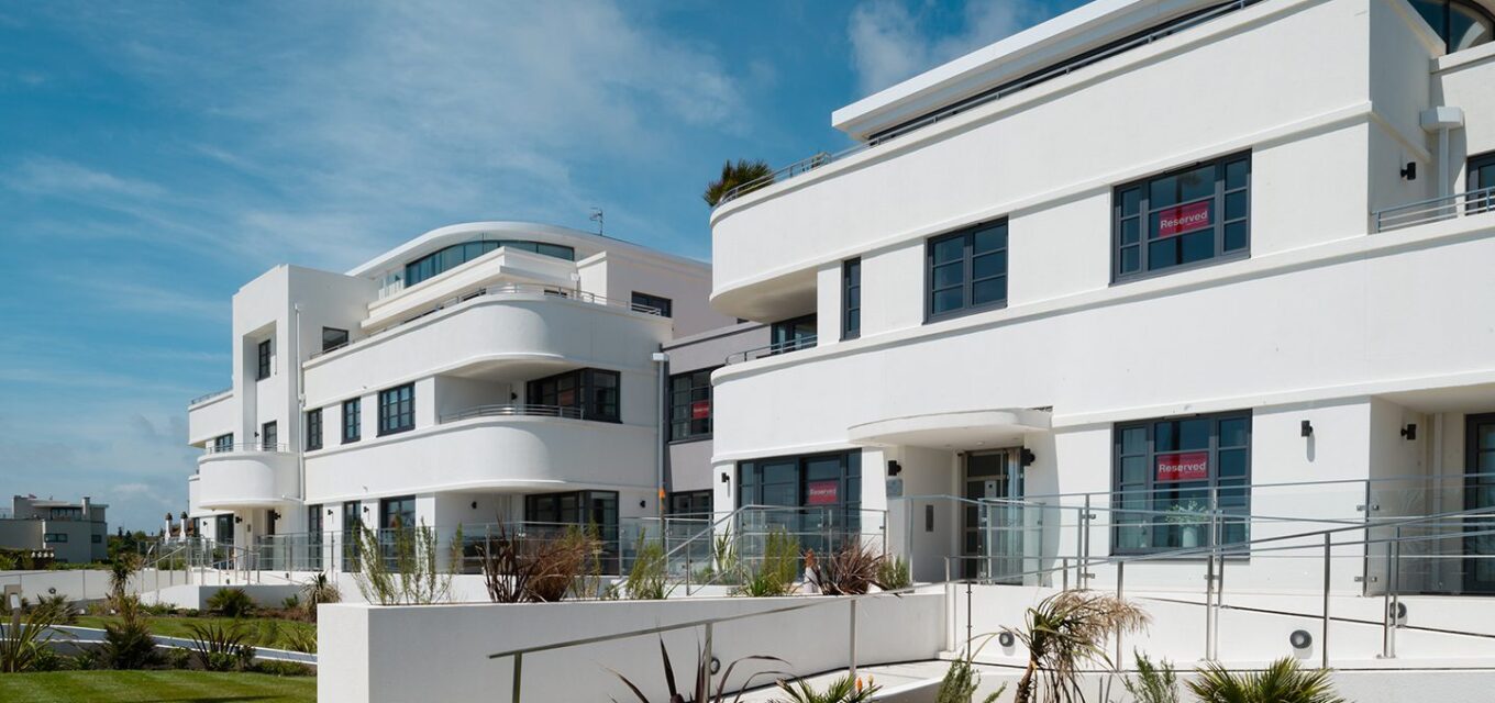 Two Art Deco-style residential flat buildings with white render, curved balconies and a ramp leading to the entrance