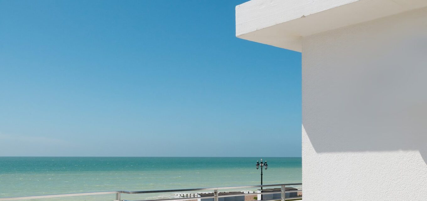 Balcony and white rendered wall looking out to the sea and seafront promenade