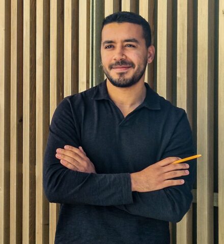 Person holding a pencil smiling at the camera.