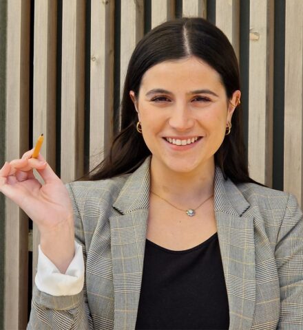 Person holding a pencil smiling at the camera.