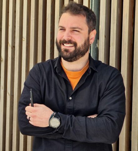 Person holding a pencil smiling at the camera.