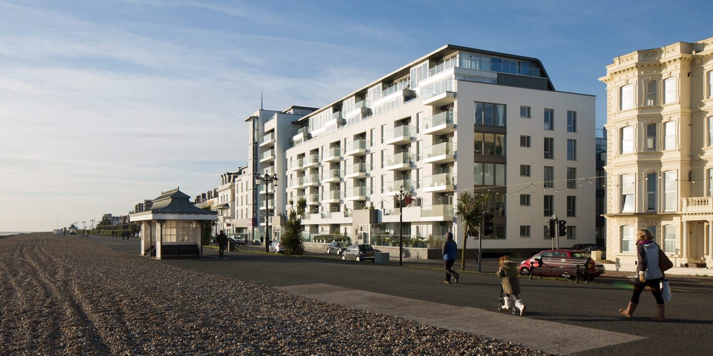 Hotel building with balconies and windows facing the sea front promenade with people walking along