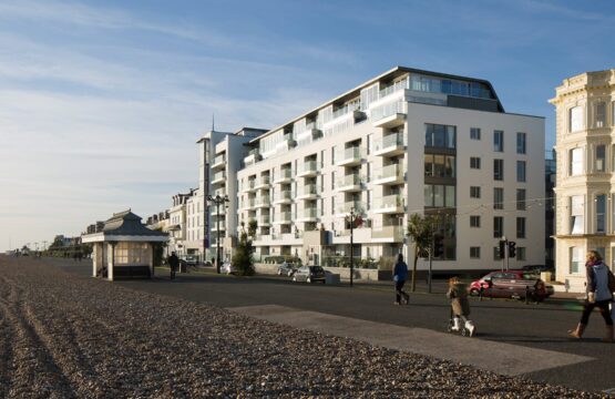 Hotel building with balconies and windows facing the sea front promenade with people walking along