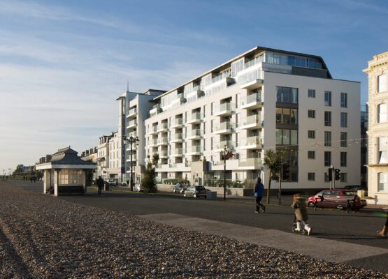 Hotel building with balconies and windows facing the sea front promenade with people walking along