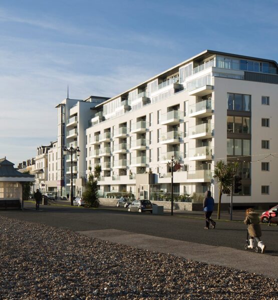 Hotel building with balconies and windows facing the sea front promenade with people walking along