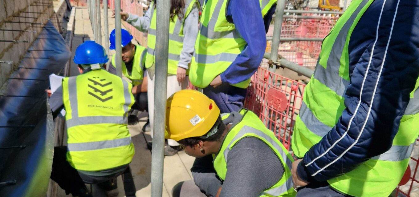 People on a construction site wearing high-vis vests and hard hats inspecting a wall.
