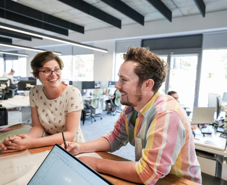 Two people in an office talking together at a desk.